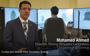 person using a driving simulator with another person in foreground 