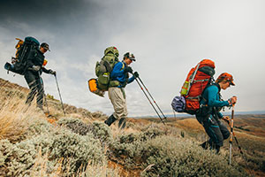 three people hiking down a hillside