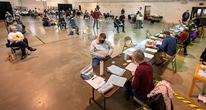 people sitting in chairs in a gymnasium with other people walking around