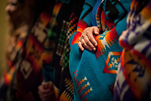 row of people wrapped in colorful blankets