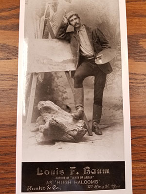 card featuring a photo of a man leaning against a painting, circa the early 1900s