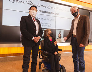 a woman and two men in front of a large banner