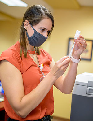 woman in mask preparing vaccine