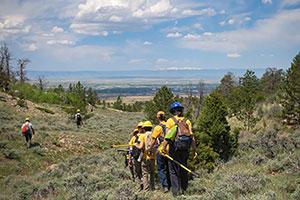 people in hardhats, tools and backpacks walking in mountins