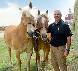 man standing with two horses