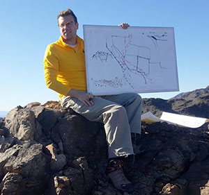 man sitting on top of rocks with a whiteboard