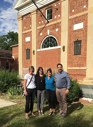 three people standing in front of an older brick building