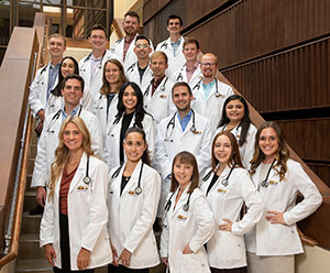 Group of people in white coats posing on stairs