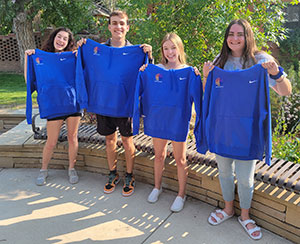 Four people holding up blue shirts