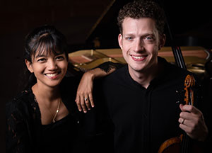 woman and man posing in front of a grand piano