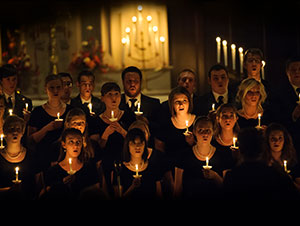 group of singers holding candles with candles in the background