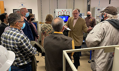 group of people on a tour of a lab with electronic equipment