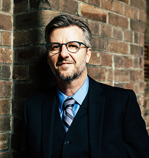 man posing in front of a brick wall