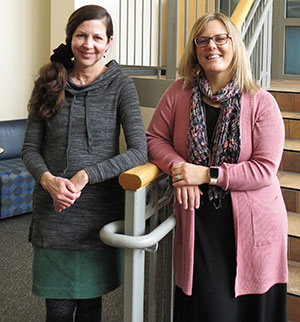 two women standing against stair railing