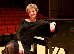 woman sitting by a grand piano