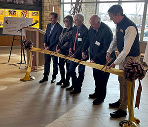 people lined up cutting a ribbon