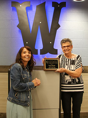 Two woman posing with an award