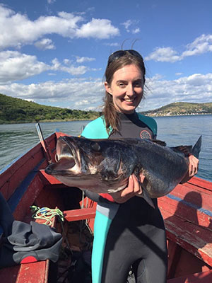 woman standing in a boat and holding a large fish