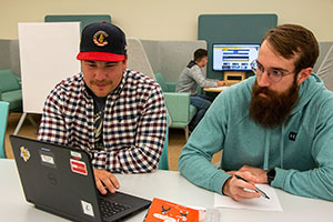 two people at a table with a laptop computer