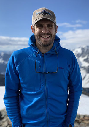 man standing in front of snowy mountains