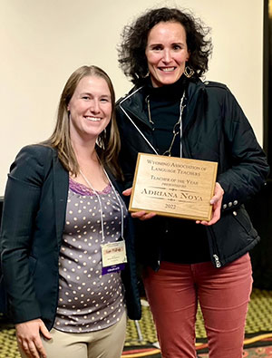 two people standing together, one holding an award