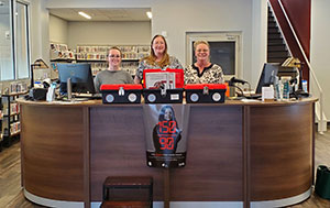 three people standing behind a desk