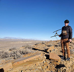 person with GPS tracking equipment on hillside overlooking the Red Desert