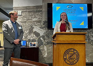 woman at podium with man standing nearby