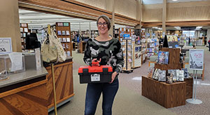 woman holding a red and black plastic box while standing in a library