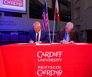 two people signing things at a table with a red cloth