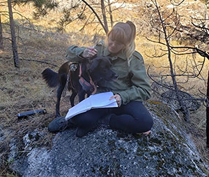 woman sitting on a rock with a dog