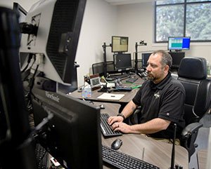 man sitting at a desk with many computer monitors on it