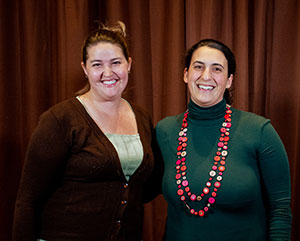 two women standing together in front of a curtain