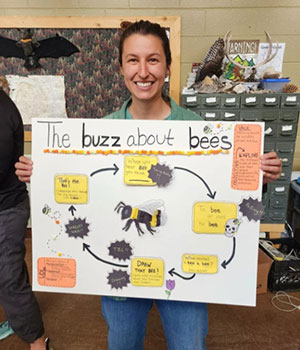 woman holding up a poster about bees