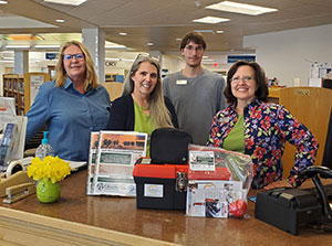 four people behind a desk with a red and black plastic box in front of them