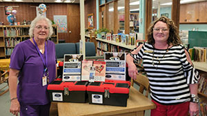 two people standing at a table with red and black plastic boxes between them