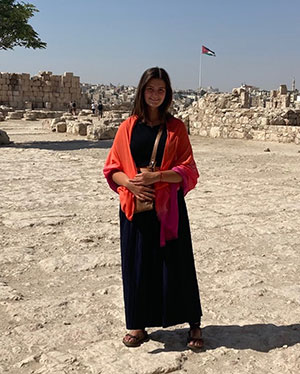 woman standing in a desert area with buildings in the backgroun