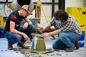two people pouring something into a concrete shape