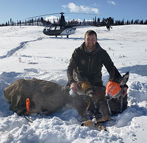 man with captured deer in the snow