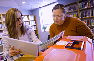 two people looking at a book with a red plastic box in the foreground