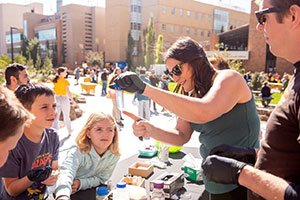 people at a table outdoors, with lots of people around