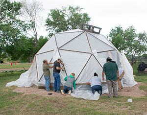 people assembling a small geodesic dome