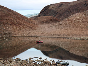 lake in hills with tiny boat on it