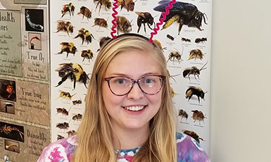 woman standing in front of a poster with insects on it