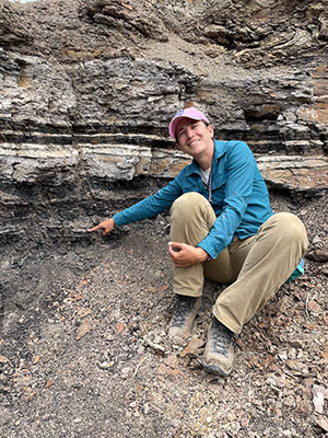 woman sitting on hillside pointing at rocks