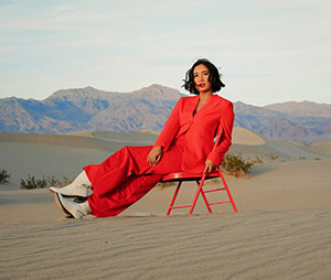 woman dressed in red sitting on a chair in a desert