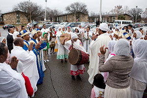 people dressed in white drumming in a crowd of people