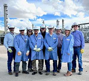group of people posing in hard hats and blue lab coats
