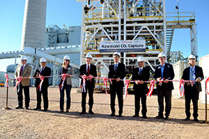 line of people in hard hats cutting ceremonial ribbon