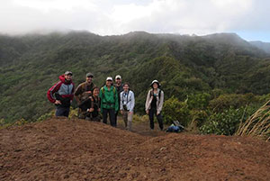 people on a hillside with cloudy mountains in the background
